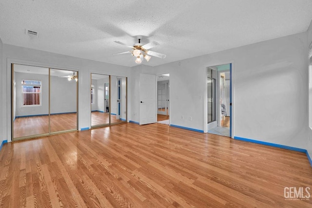 unfurnished living room with ceiling fan, light wood-type flooring, and a textured ceiling