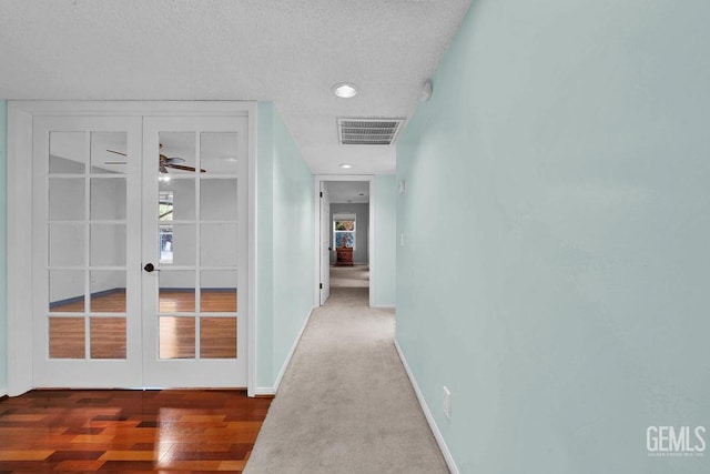 hall with french doors, a textured ceiling, and wood-type flooring