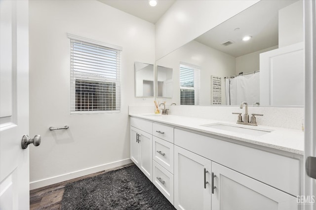 bathroom with baseboards, visible vents, a sink, and double vanity