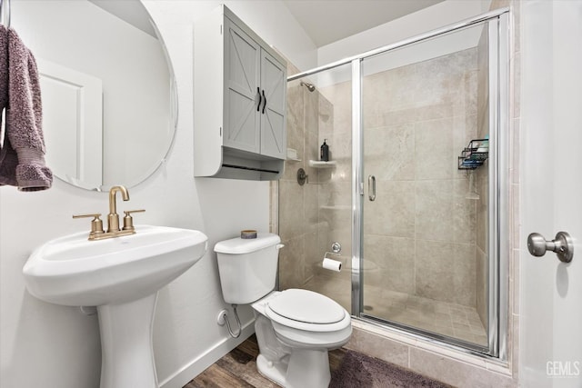 full bath featuring wood finished floors, toilet, a stall shower, and a sink