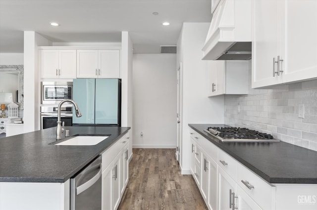 kitchen with stainless steel appliances, decorative backsplash, dark countertops, and premium range hood
