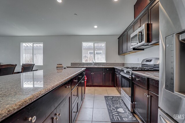 615 Welch Ave, Bakersfield, CA 93307 - kitchen featuring appliances with stainless steel finishes, light tile patterned flooring, recessed lighting, a sink, and dark stone countertops