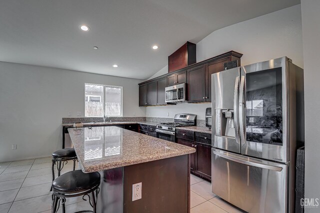 615 Welch Ave, Bakersfield, CA 93307 - kitchen with appliances with stainless steel finishes, vaulted ceiling, a center island, a breakfast bar area, and dark brown cabinets
