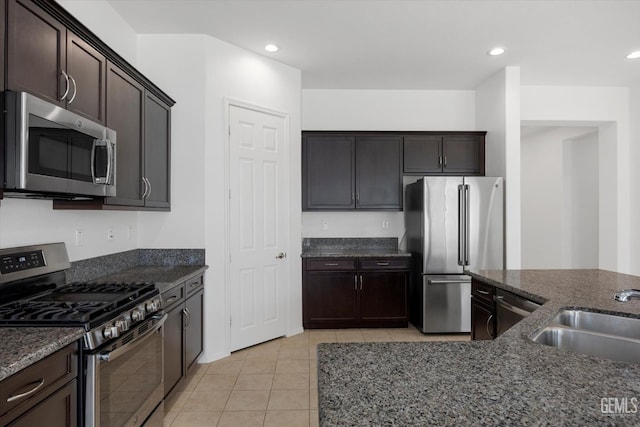 9702 Petersburg Pl, Bakersfield, CA 93306 - kitchen featuring stainless steel appliances, a sink, dark stone counters, dark brown cabinetry, and light tile patterned floors