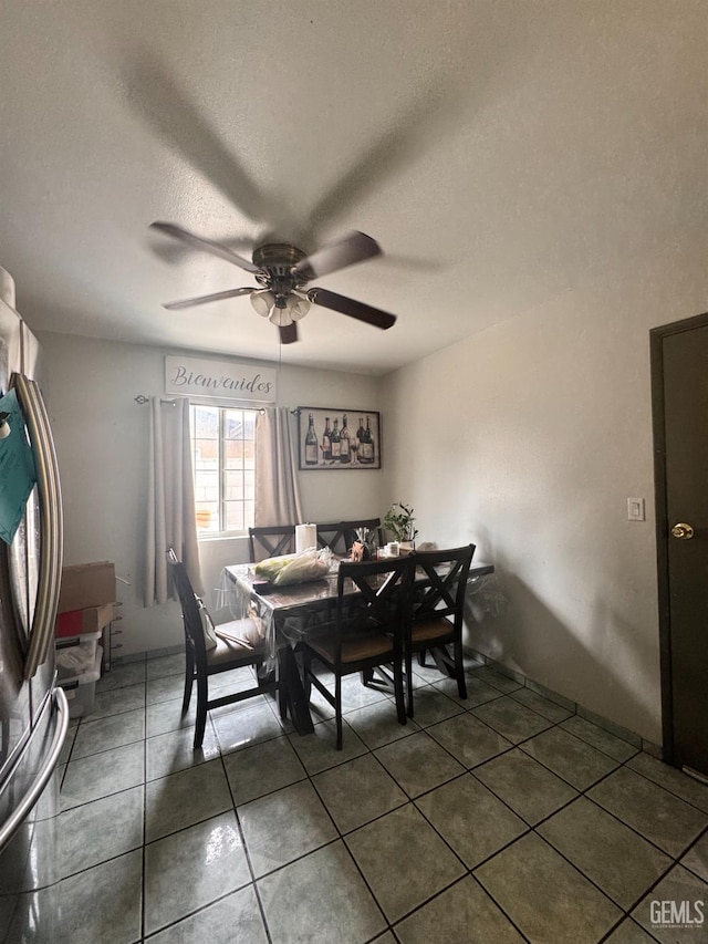 dining room featuring ceiling fan, dark tile patterned floors, and a textured ceiling