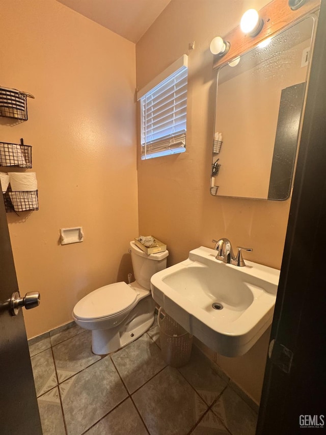 bathroom featuring tile patterned flooring, toilet, and a sink