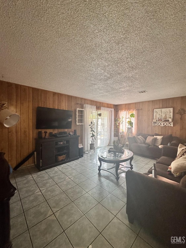 living room featuring wooden walls, a textured ceiling, and tile patterned flooring