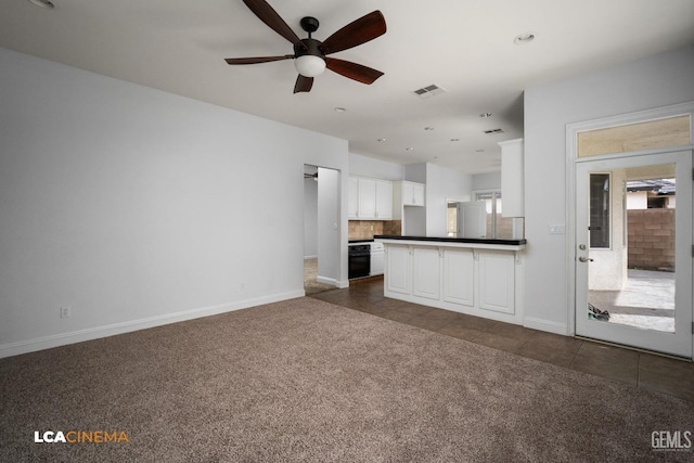 unfurnished living room featuring baseboards, visible vents, a ceiling fan, dark carpet, and dark tile patterned floors