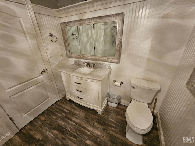 bathroom featuring baseboards, wood finished floors, toilet, and vanity
