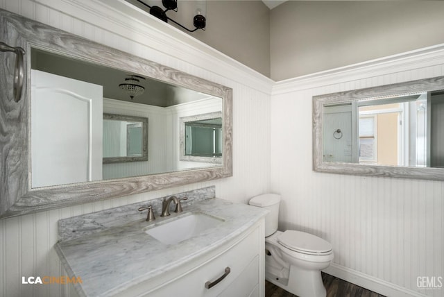 bathroom featuring baseboards, wood finished floors, toilet, and vanity