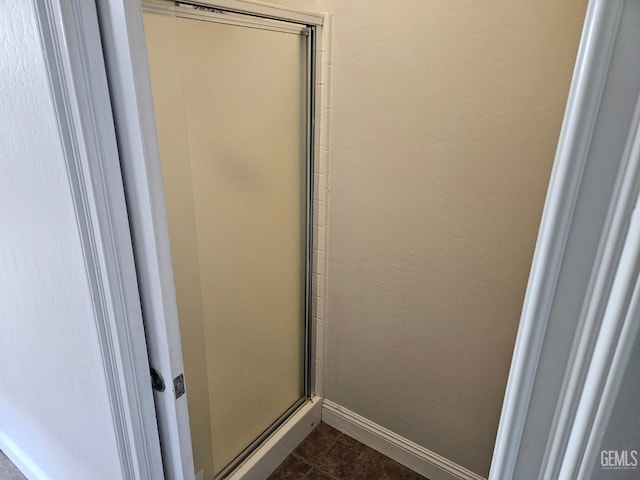 full bath with a shower stall and baseboards