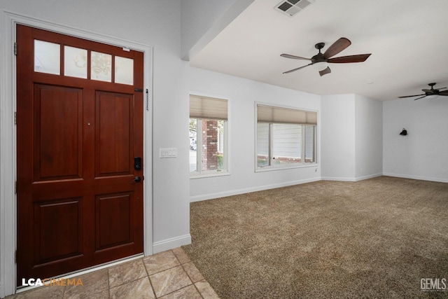 foyer entrance featuring light colored carpet, baseboards, a ceiling fan, and visible vents