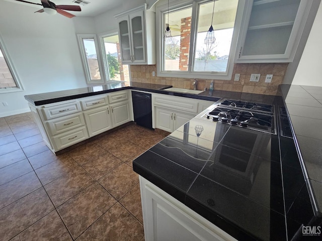 kitchen with dishwasher, a peninsula, tasteful backsplash, and glass insert cabinets