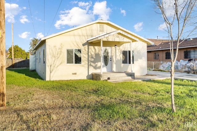 back of property with crawl space, a yard, stucco siding, and fence