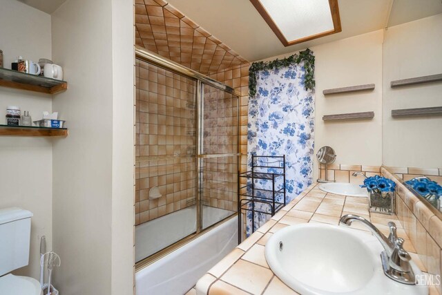 bathroom with enclosed tub / shower combo, toilet, a sink, and double vanity