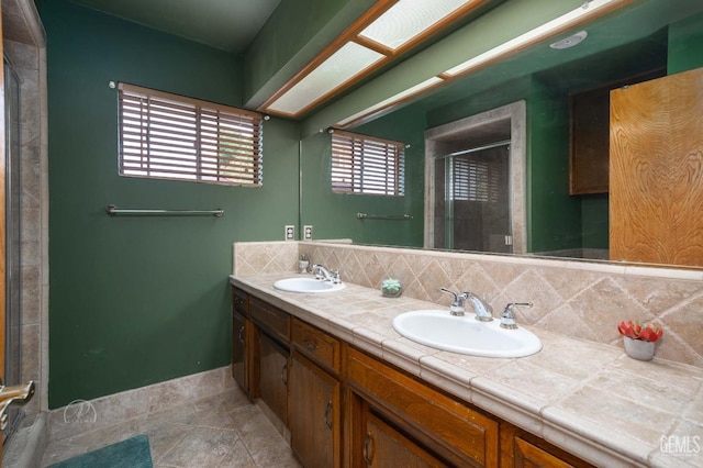 full bathroom featuring a shower stall, backsplash, a sink, and double vanity
