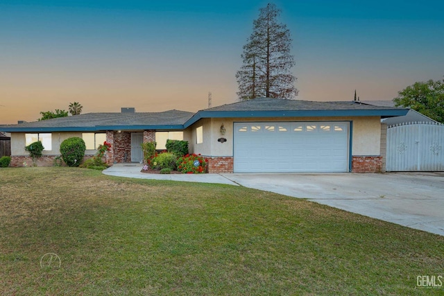 view of front of house with concrete driveway, brick siding, a garage, a yard, and stucco siding