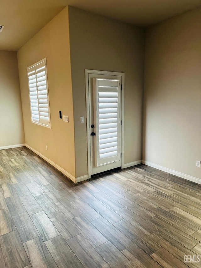 unfurnished room featuring baseboards, visible vents, and wood finished floors