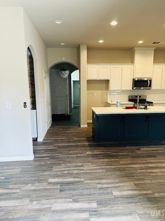 kitchen featuring arched walkways, dark wood-style flooring, white cabinetry, and stainless steel appliances
