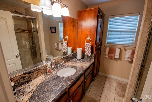 bathroom featuring vanity, baseboards, a stall shower, tile patterned floors, and toilet