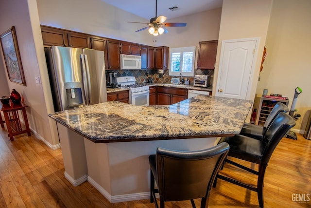 kitchen featuring visible vents, a ceiling fan, a sink, tasteful backsplash, and white appliances