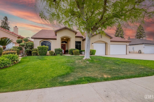 mediterranean / spanish house with a tiled roof, stucco siding, a lawn, driveway, and an attached garage