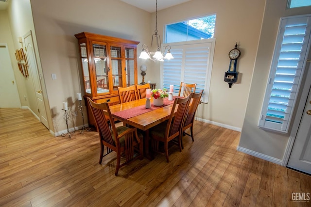 dining room with baseboards, light wood-style floors, and an inviting chandelier