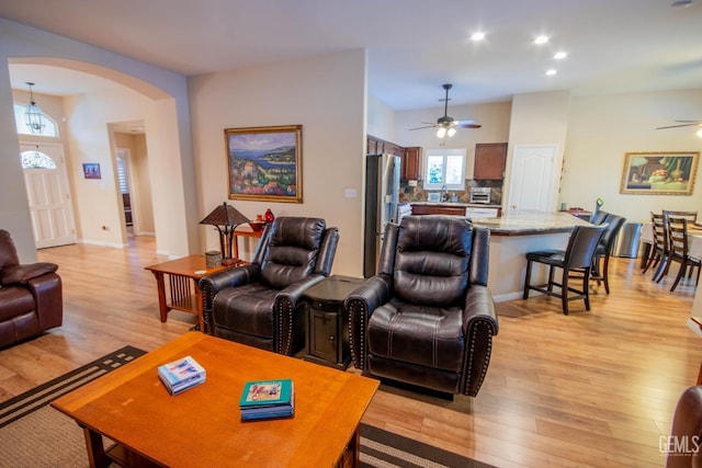 living area with arched walkways, recessed lighting, light wood finished floors, and ceiling fan