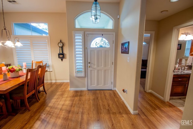 foyer featuring light wood-type flooring, baseboards, and a notable chandelier