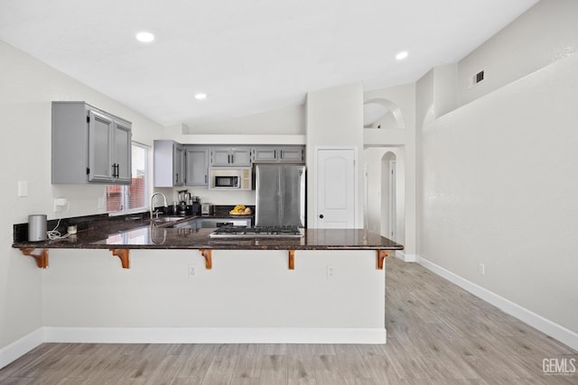 kitchen with sink, gray cabinetry, a kitchen breakfast bar, stainless steel appliances, and kitchen peninsula