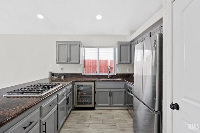 kitchen featuring appliances with stainless steel finishes, sink, gray cabinetry, and wine cooler