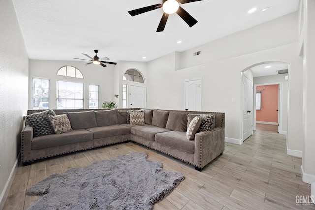 living room with ceiling fan, high vaulted ceiling, and light hardwood / wood-style flooring