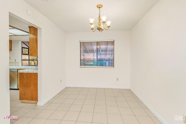 tiled empty room with sink, a textured ceiling, and a chandelier