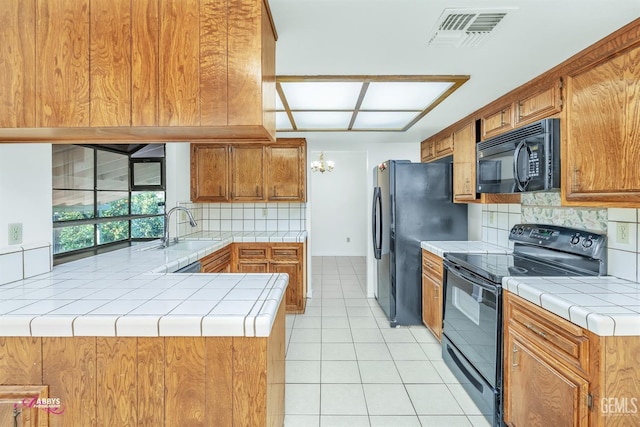 kitchen featuring tasteful backsplash, tile countertops, black appliances, kitchen peninsula, and sink