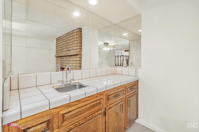 kitchen with light tile patterned floors, tile counters, and sink