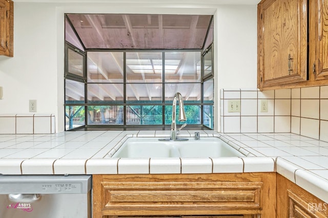 kitchen with decorative backsplash, sink, dishwasher, and tile counters