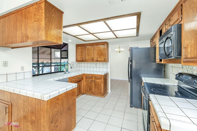 kitchen with backsplash, tile countertops, black appliances, kitchen peninsula, and sink