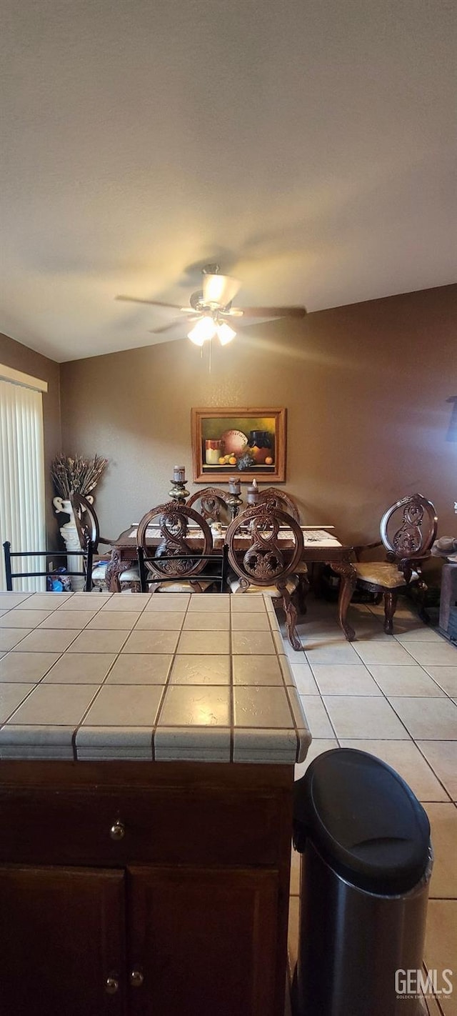 kitchen featuring dark brown cabinetry, ceiling fan, tile counters, and light tile patterned floors