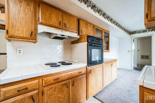 kitchen with tasteful backsplash, tile countertops, white electric cooktop, and oven