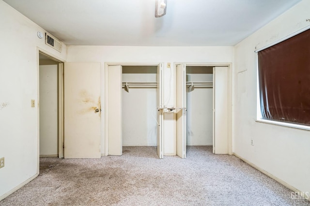 unfurnished bedroom with light colored carpet and multiple closets