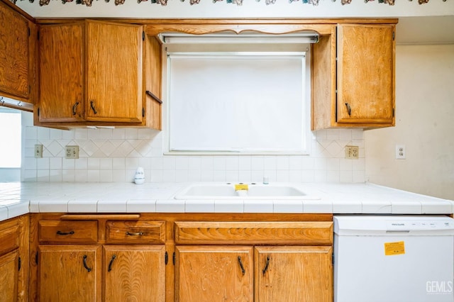 kitchen featuring backsplash, tile countertops, dishwasher, and sink