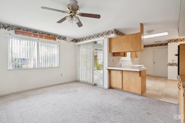 kitchen with kitchen peninsula, ceiling fan, and light colored carpet