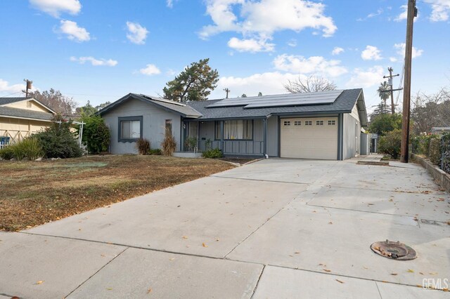 ranch-style home with solar panels, a garage, and a front yard