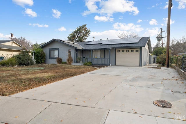 ranch-style home with solar panels, a garage, and a front yard