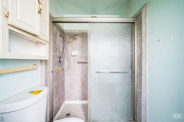 bathroom featuring toilet and a shower with shower door