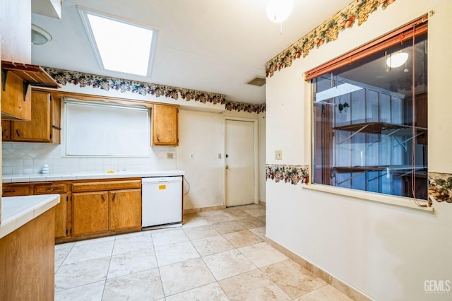 kitchen with backsplash, white dishwasher, and tile counters