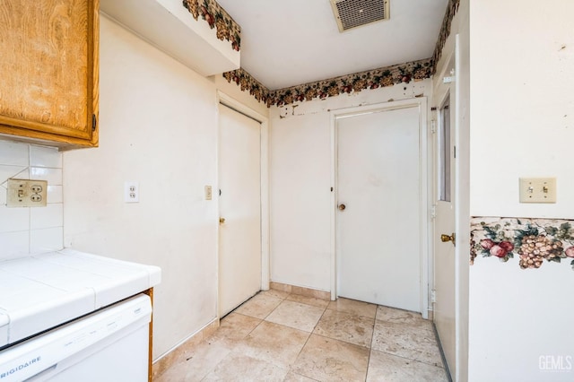 interior space featuring tile countertops, backsplash, and white dishwasher