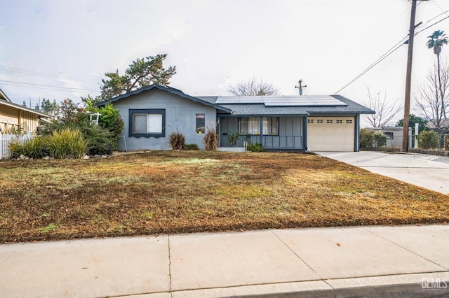 ranch-style house with a front yard, solar panels, and a garage