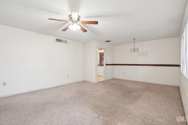 unfurnished room featuring ceiling fan with notable chandelier and carpet floors