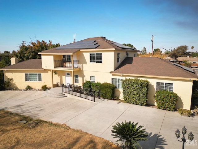 front of property with solar panels and a balcony